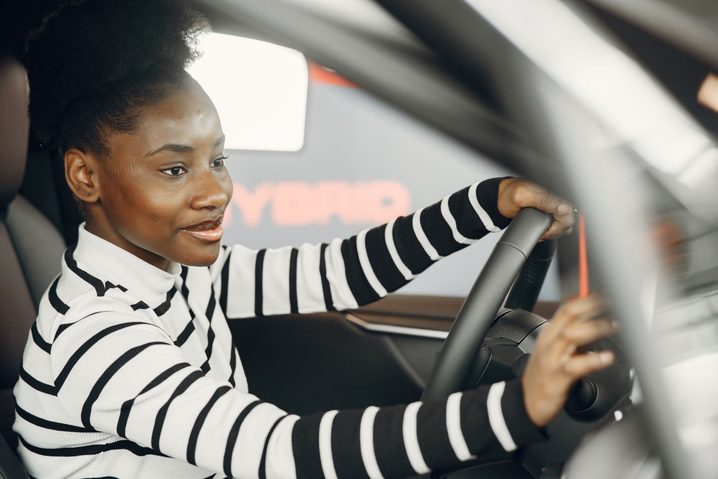 A smiling learner driver with both hands on the wheel